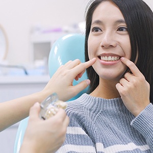 Woman in dentist’s chair pointing to her tooth